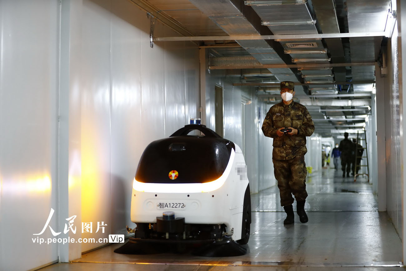 2月26日，武汉火神山医院，洗消分队队长张鹏飞在操控机器人对走廊进行消毒作业。