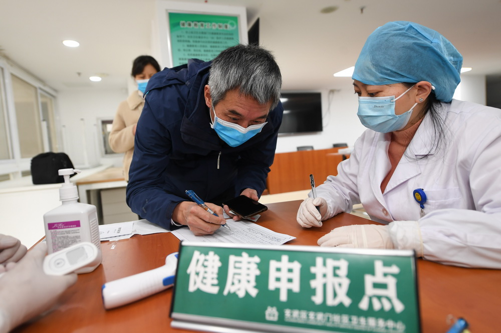 1月21日，在南京市玄武区玄武门社区卫生服务中心，来自江苏省肿瘤医院的一线医务人员（左）在疫苗接种前进行健康申报。