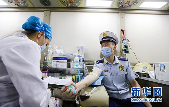 在武汉街头，一名青年消防员在献血车内无偿献血。新华网发 王方摄