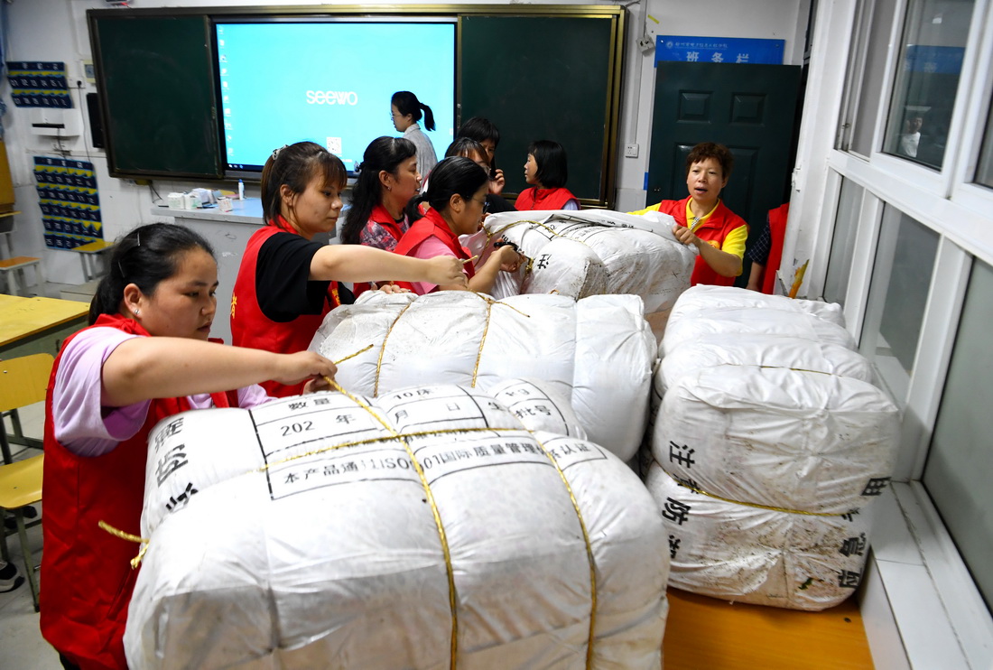 7月21日，在鄭州市電子信息工程學校集中安置點，志愿者在整理被褥。