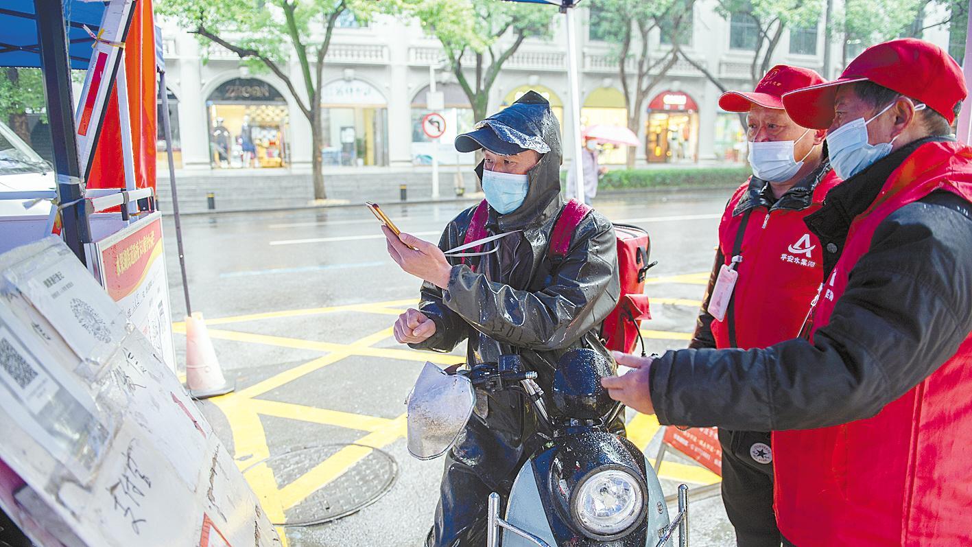 10月20日，在武漢市武昌區(qū)水果湖街道放鷹臺(tái)社區(qū)入口，社區(qū)志愿服務(wù)隊(duì)隊(duì)員正在引導(dǎo)進(jìn)出社區(qū)人員掃碼測(cè)溫。